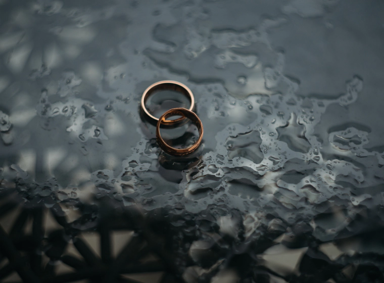 golden marriage rings on top of a black glass table